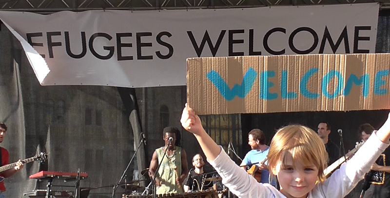 Carteles de bienvenida a refugiados en un concierto