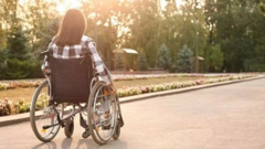 Imagen de una mujer en silla de ruedas paseando por un parque