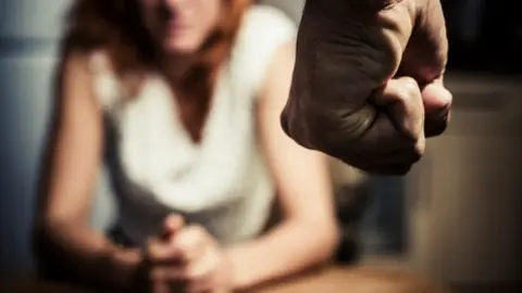 Detalle de una mujer desenfocada al fondo y en primer plano un puño de un hombre