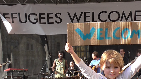 Carteles de bienvenida a refugiados en un concierto