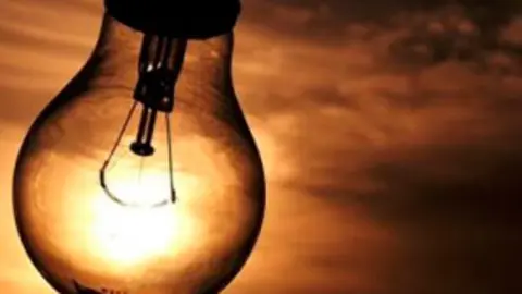 Detalle de una bombilla del revés a través de la que se ve el sol 