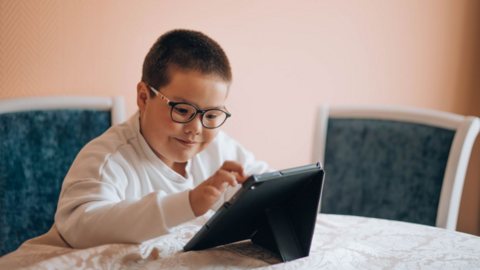 Imagen de un niño con discapacidad que lee en una tableta digital